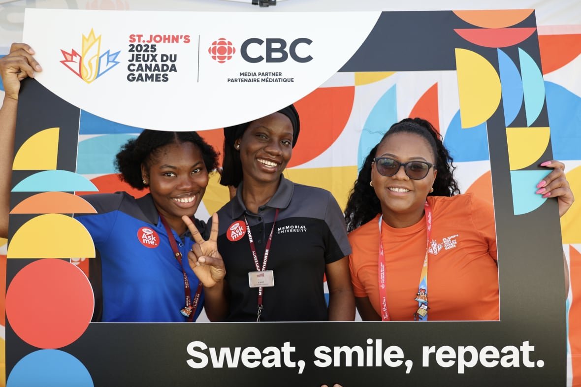 Volunteers posing with a large CBC and 2025 Canada Games photo frame at the CBC Pop-Up Photo Studio. One volunteer making a peace sign with two fingers.