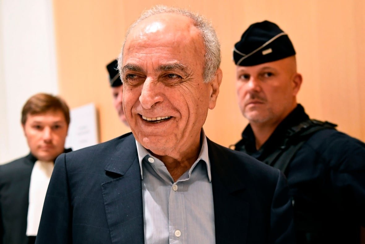 A man in a blazer and collared shirt smiling