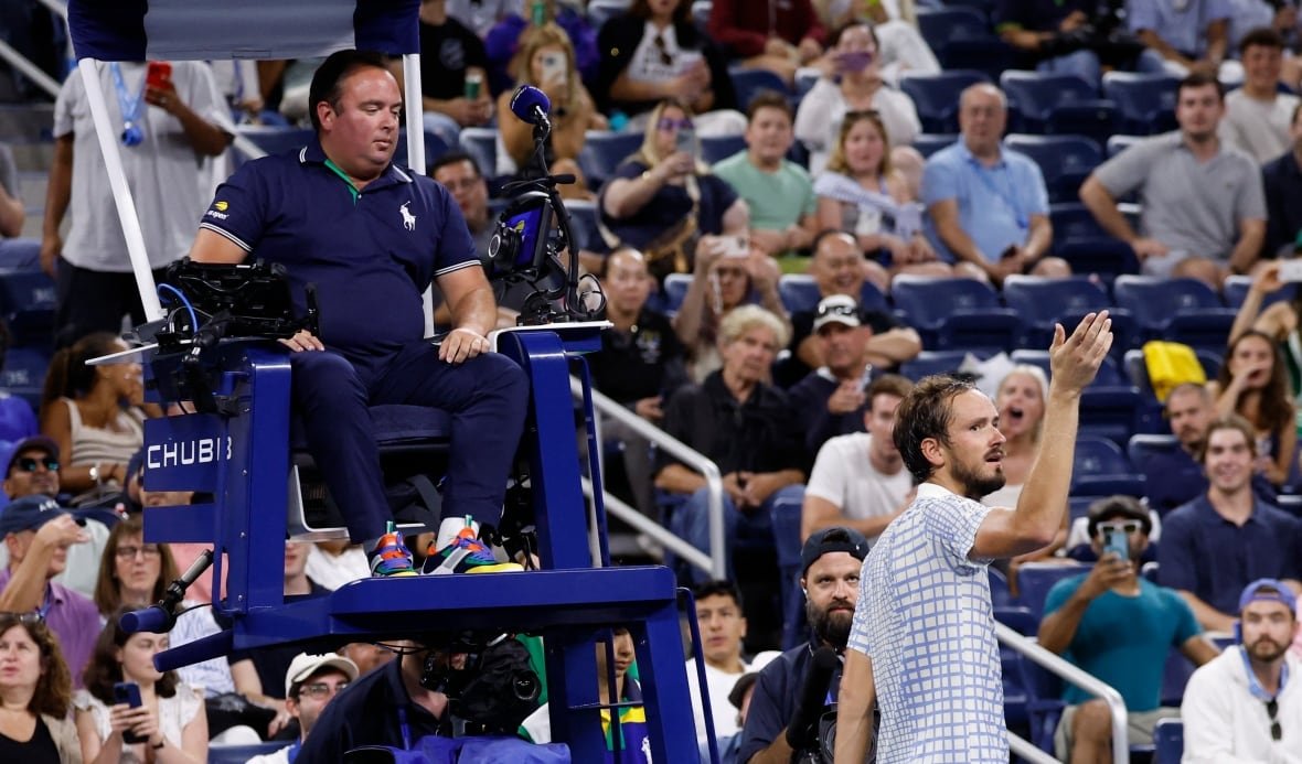 A man converses with a referee in front of a crowd
