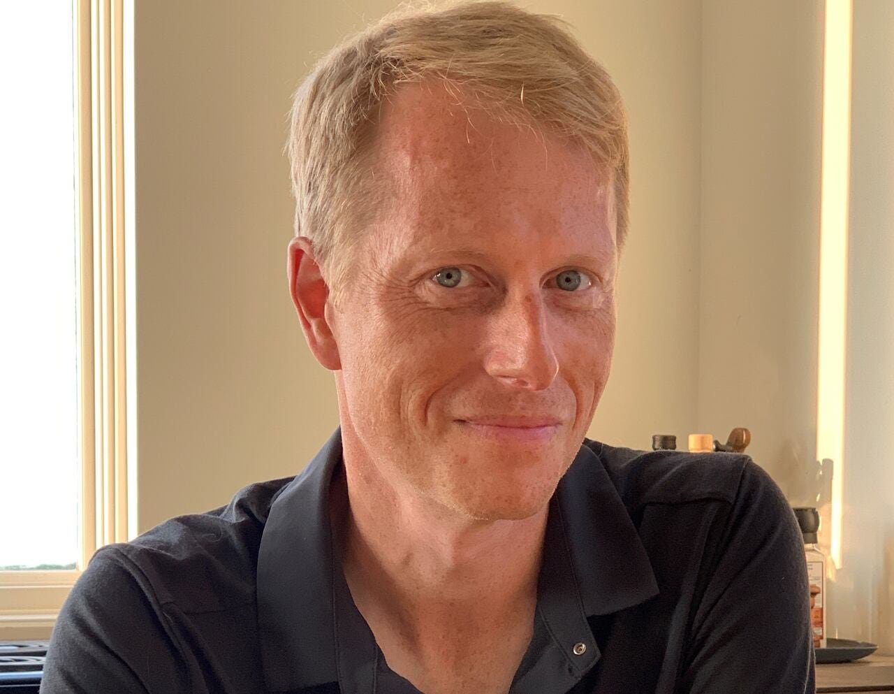 default-202 A headshot of a smiling man weating a black polo shirt.