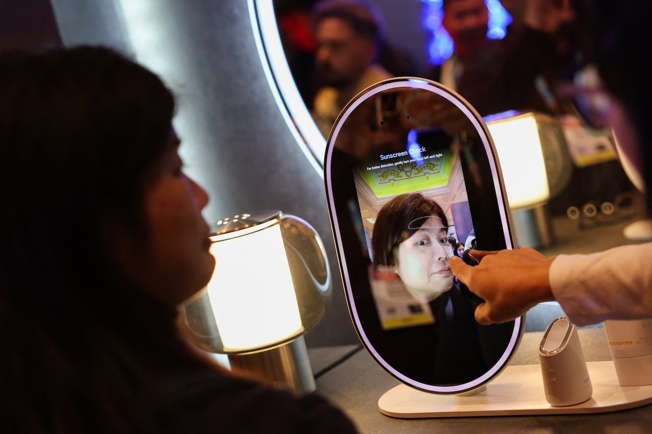 default-207 A person interacting with an oval screen-mirror, with another person's hand pointing at the reflection.