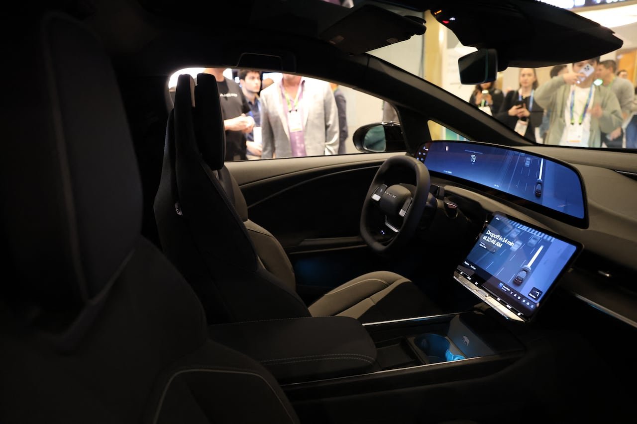 default-211 Profile view of a vehicle interior surrounded by people at a trade show.