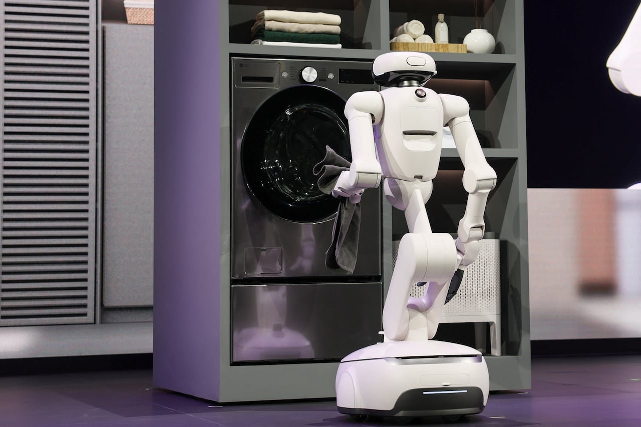 default-212 A white robot loading laundry into a washing machine during a stage demo.